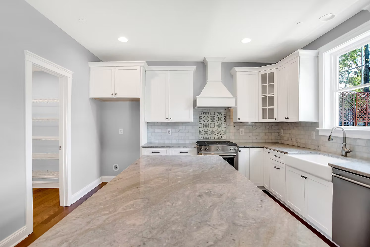 Custom kitchen with large marble island and white cabinetry